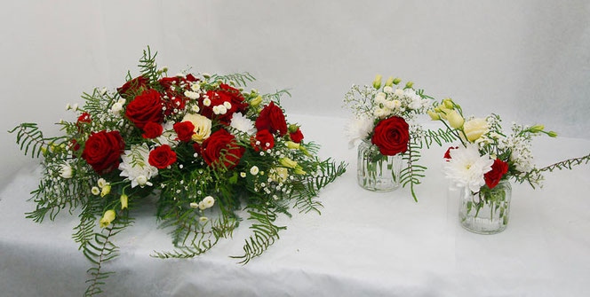Tischgesteck und kleine Vasen als Tischdeko mit roten Rosen